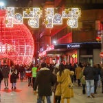 Transeúntes pasean bajo las luces navideñas, en Vigo, Galicia (España),