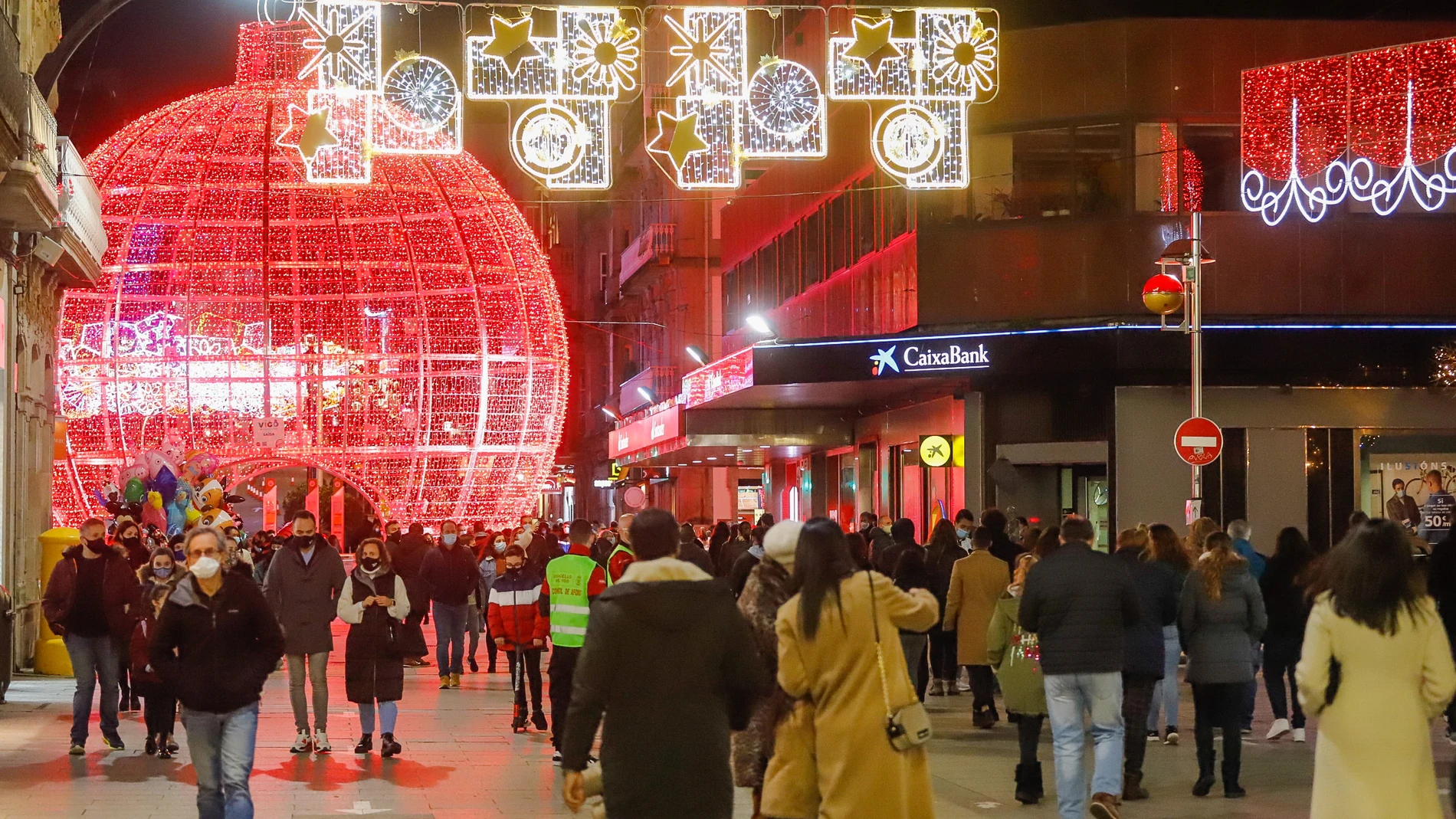 Transeúntes pasean bajo las luces navideñas, en Vigo, Galicia (España),