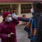 An exile Tibetan Buddhist nun moves her cap to allow her body temperature be taken as a precaution against the coronavirus before casting her vote inDharmsala, India, Sunday, Jan. 3, 2021. Exile Tibetans Sunday voted in the first round to elect a new political leader and members of the Tibetan parliament in exile. (AP Photo/Ashwini Bhatia)