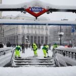 Operarios trabajan para retirar nieve y mejorar la circulación en la Puerta del Sol en Madrid, este sábado