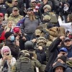 Una fila de hombres con cascos y chalecos antibalas de color verde oliva suben las escaleras de mármol del Capitolio de los EE. UU