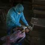 FILE - In this Sept. 30, 2020, file photo, an Indian health worker takes a nasal swab sample of a student to test for coronavirus after classes started at a college in Jhargaon village, outskirts of Gauhati, India. The global death toll from COVID-19 has topped 2 million. (AP Photo/Anupam Nath, File)