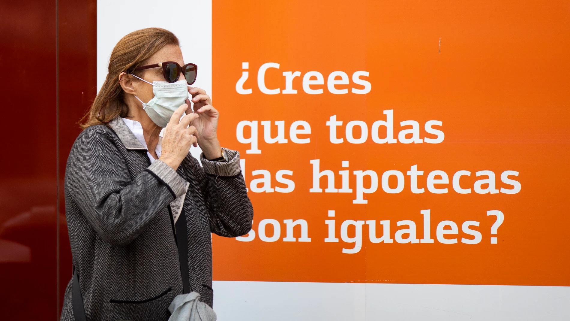 Una mujer pasa por delante de un banco que anuncia hipotecas