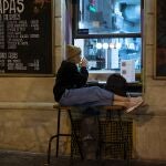 Una joven bebe una copa de vino sola en el exterior de un bar de Barcelona