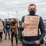 Un hombre con un cártel en el que se lee: `No somos culpables, déjenos trabajar´ durante una caravana reivindicativa de hosteleros y comerciantes