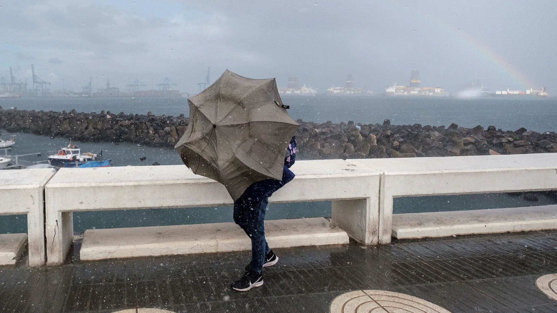 Una persona intenta avanzar ante el fuerte viento y la lluvia