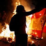 Un manifestante independentista con una bandera de España y junto a una hoguera, durante las manifestaciones de la última Diada