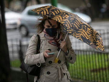 Una mujer camina bajo su paraguas durante un d&iacute;a lluvioso y con rachas de viento 