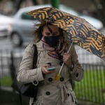 Una mujer camina bajo su paraguas durante un d&iacute;a lluvioso y con rachas de viento 