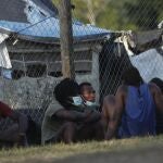 Haitian migrants sit on the grass at a migrant camp amid the new coronavirus pandemic in San Vicente, Darien province, Panama, Tuesday, Feb. 9, 2021. Panama is allowing hundreds of migrants stranded because of the pandemic, to move to the border with Costa Rica, after just reopening its land borders. (AP Photo/Arnulfo Franco)