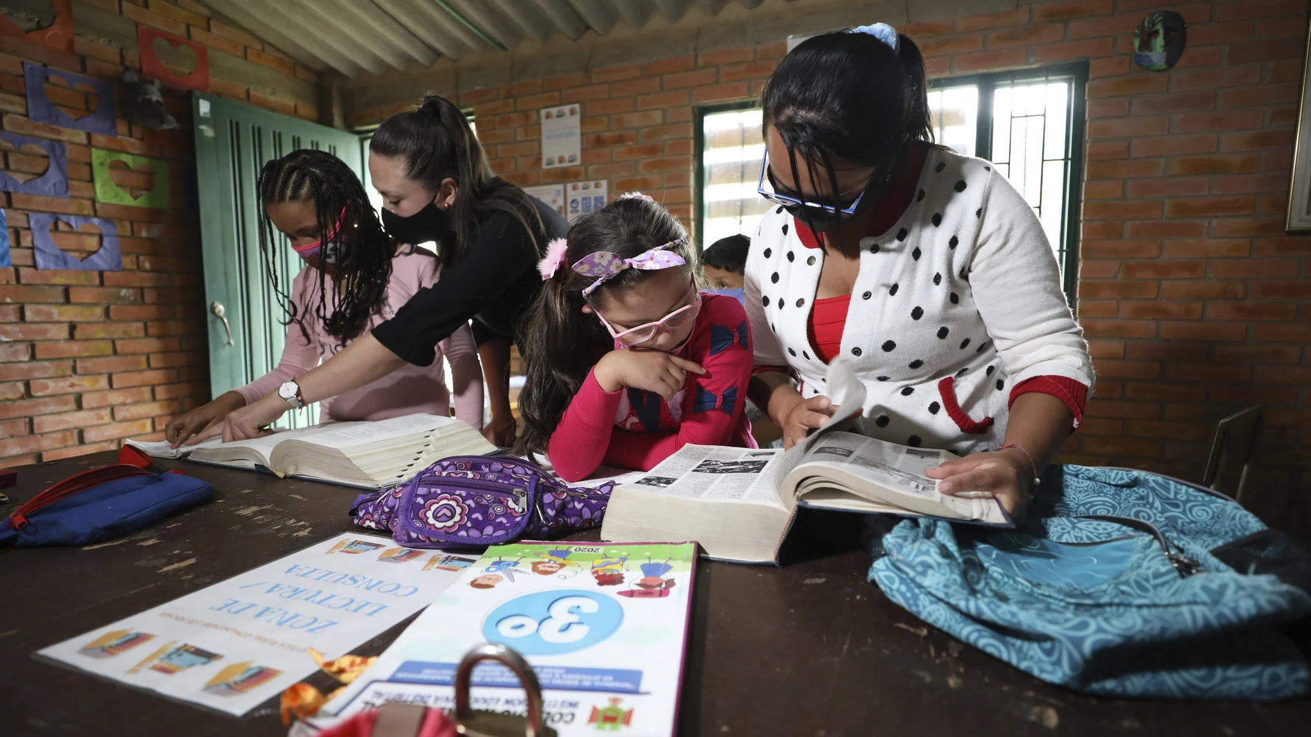 Ana Milena Liberato, right, reads a book with her daughter Wendy Valeria, as they do her biology homework at Los Soches Rural Community Library in Los Soches, a small rural village on the outskirts of Bogota, Colombia, Wednesday, Feb. 10, 2021. Every month Liberato must allocate 50,000 pesos (approximately 15 dollars) to buy internet packages, although in the middle of the new coronavirus pandemic she lost her job. (AP Photo/Fernando Vergara)