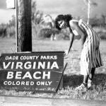Fotografía de los años 40 cedida por el Parque Histórico de Virginia Key Beach donde aparece una mujer señalando un cartel que dice "Solo para gente de color" derribado por un huracán en la segregada playa de Virginia en la Bahía Vizcaína, en Miami