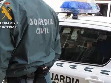 Un agente de la Guardia Civil, junto a un coche patrulla Un agente de la Guardia Civil, junto a un coche patrulla