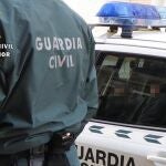 Un agente de la Guardia Civil, junto a un coche patrulla