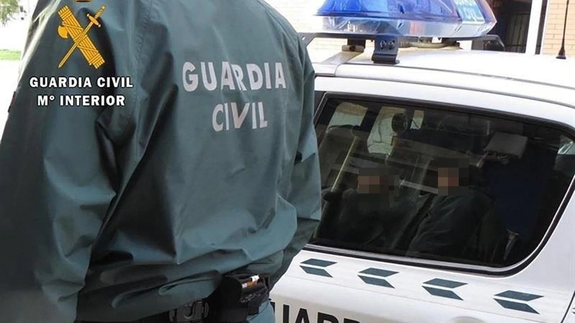 Un agente de la Guardia Civil, junto a un coche patrulla