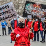 Una mujer sostiene una pancarta donde se lee "¡Queremos trabajar!" durante una protesta en la Plaza del Ayuntamiento, en Valencia