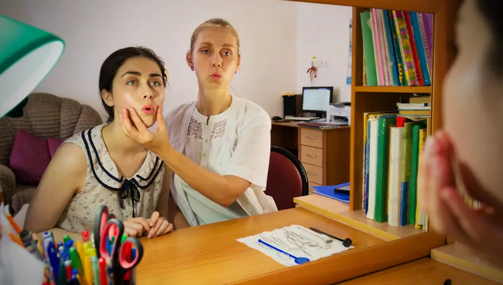 Logopeda enseña a una niña la pronunciación correcta del habla