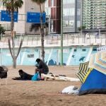 Tres inmigrantes descansan en la playa de las Alcaravaneras, en Las Palmas de Gran Canaria