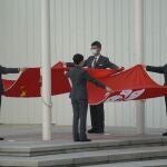 Miembros del personal doblan las banderas de China y Hong Kong en el Consejo Legislativo en Hong Kong, hoy