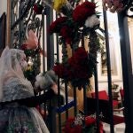 Una fallera deposita un ramo de flores frente a la Virgen