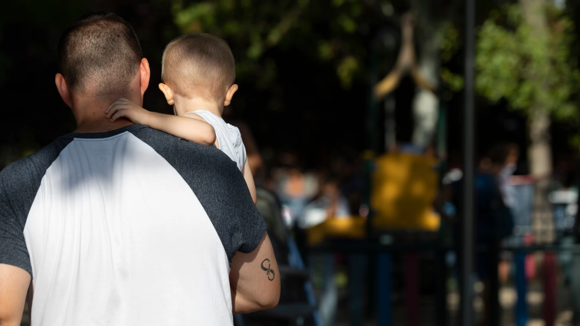 Un padre cogiendo su hijo en un parque