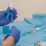 Una profesional sanitaria sostiene una jeringuilla junto a un vial con la vacuna de AstraZeneca