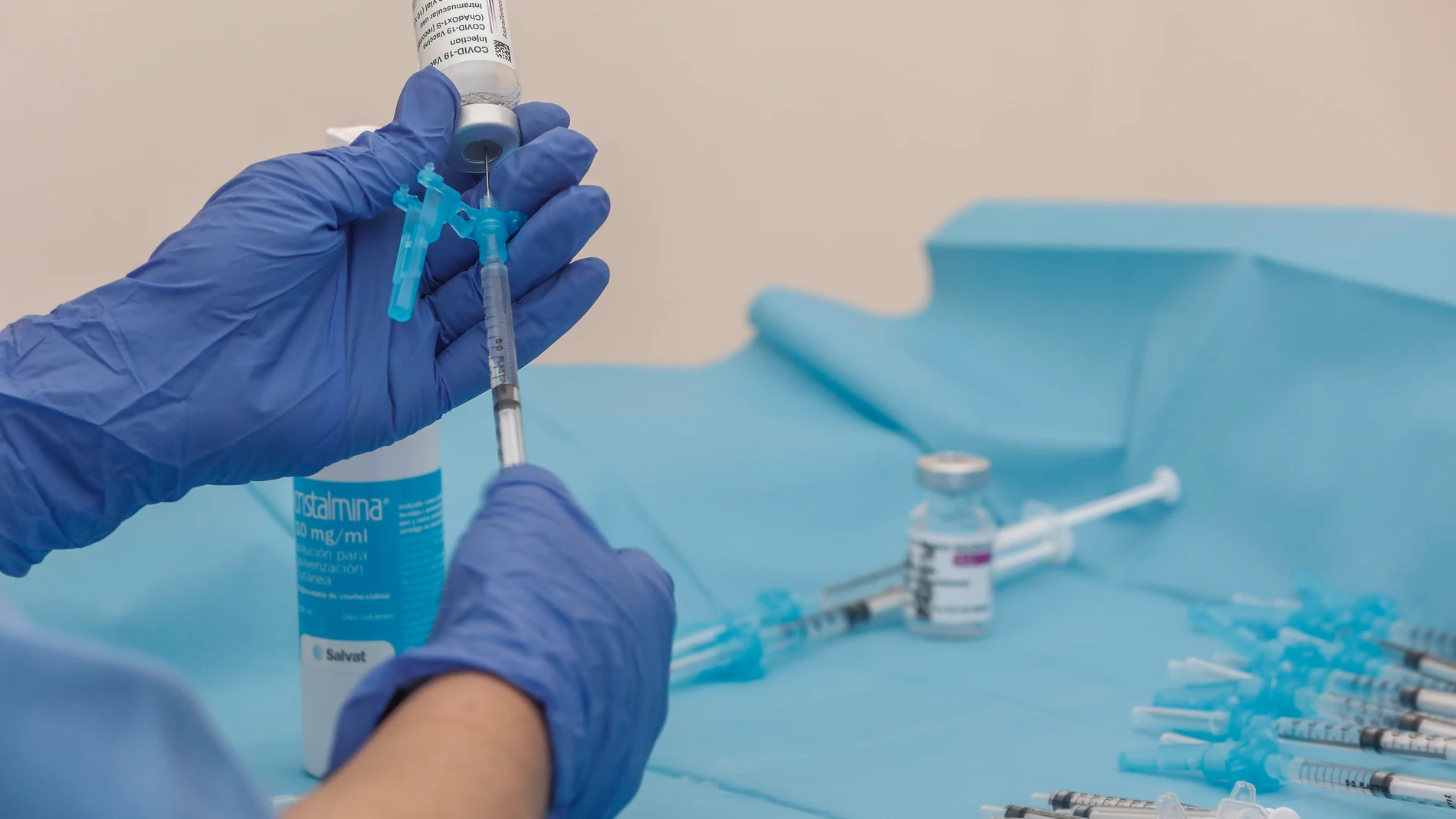 Una profesional sanitaria sostiene una jeringuilla junto a un vial con la vacuna de AstraZeneca