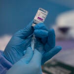 Imagen de archivo de una profesional sanitaria sosteniendo una jeringuilla con un vial de la vacuna contra la COVID-19 de AstraZeneca en un dispositivo de vacunación en el pabellón SADUS en Sevilla