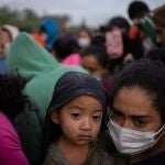 Keylin, una migrante hondureña en busca de asilo, sostiene a su hijo Olban, de tres años, en medio de docenas de otras personas mientras esperan subir a un autobús de la patrulla fronteriza