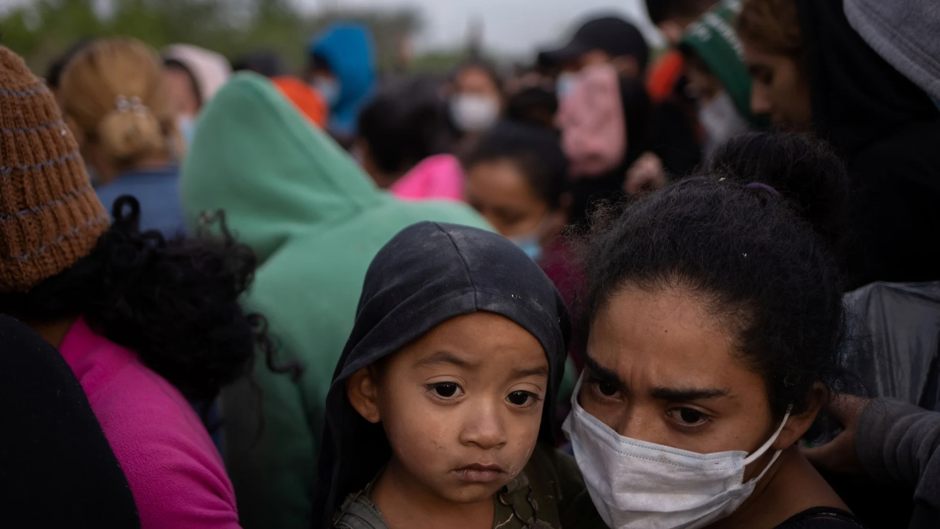 Keylin, una migrante hondureña en busca de asilo, sostiene a su hijo Olban, de tres años, en medio de docenas de otras personas mientras esperan subir a un autobús de la patrulla fronteriza