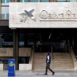 Un hombre observa el logo de Caixabank en la sede social en Valencia
