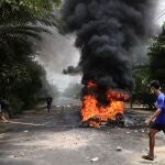 Varios manifestantes pasan junto a neumáticos en llamas después de que los activistas llevaran a cabo una "huelga de basura" contra la Junta Militar en Rangún