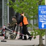 Un operario ayuda a un hombre que va a ser vacunado con la dosis de Pfizer en el pabellón de Expocoruña