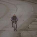 Un hombre circula con su bicicleta entre una nube de cenizas provocada por el volcán La Soufriere
