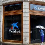Una mujer que observa el interior de la sede de CaixaBank en la plaza del Ayuntamiento de Valencia