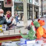Unos clientes buscan libros en una conocida librería del centro de Barcelona, que ha colocado su puesto de venta en la calle para anticipar y evitar las habituales aglomeraciones en su establecimiento mañana Diada de Sant Jordi, día del libro y de la rosa.