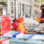 Una cliente busca libros en una conocida librería del centro de Barcelona, ha colocado su puesto de venta en la calle para anticipar y evitar las habituales aglomeraciones en su establecimiento mañana Diada de Sant Jordi, día del libro y de la rosa.