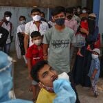 A health worker takes a mouth swab sample of a man to test for COVID-19 as others wait their turn to get tested at a hospital in Hyderabad, India, Monday, April 19, 2021. (AP Photo/Mahesh Kumar A.)