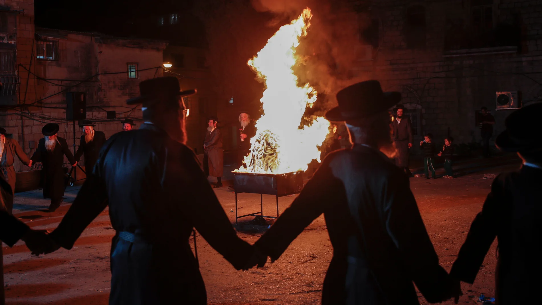Judíos ultraortodoxos bailan alrededor de una gran hoguera en el barrio ortodoxo de Mea Shearim en Jerusalén, Israel