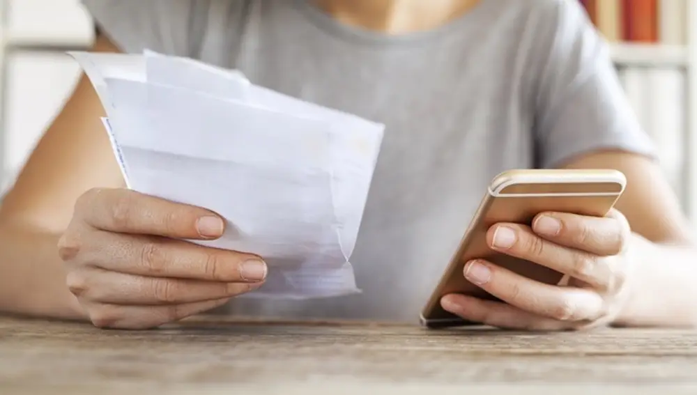 Persona sujeta un teléfono y una factura
