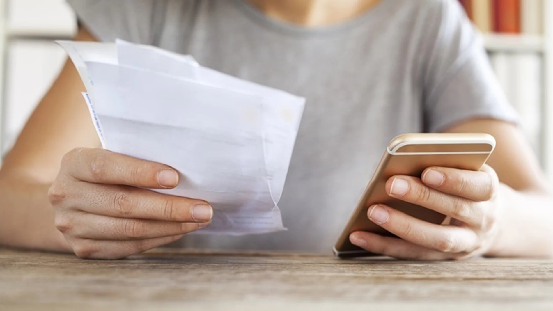 Persona sujeta un teléfono y una factura