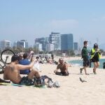 Dos operarios del Ayuntamiento de Barcelona controlan el aforo de las siempre concurridas playas de la capital catalana, un dispositivo de control que se activa esta semana
