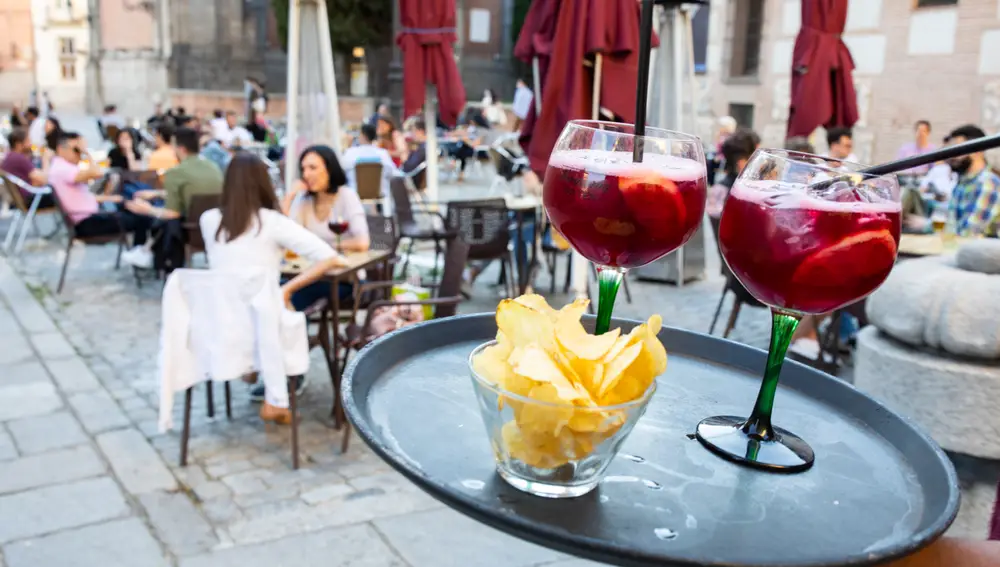 Un camarero llevando dos tintos de verano a una mesa de una terraza en Madrid