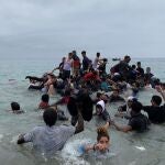 Un grupo de personas se hacen con una embarcación de las autoridades marroquíes en la playa de la localidad de Fnideq (Castillejos) para cruzar los espigones de Ceuta este martes