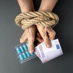 Manos atadas con dinero y pastillas