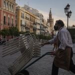 Un camarero recoge el mobiliario de la terraza de un bar en Sevilla