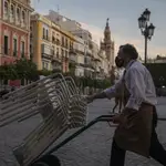 Un camarero recoge el mobiliario de la terraza de un bar en Sevilla
