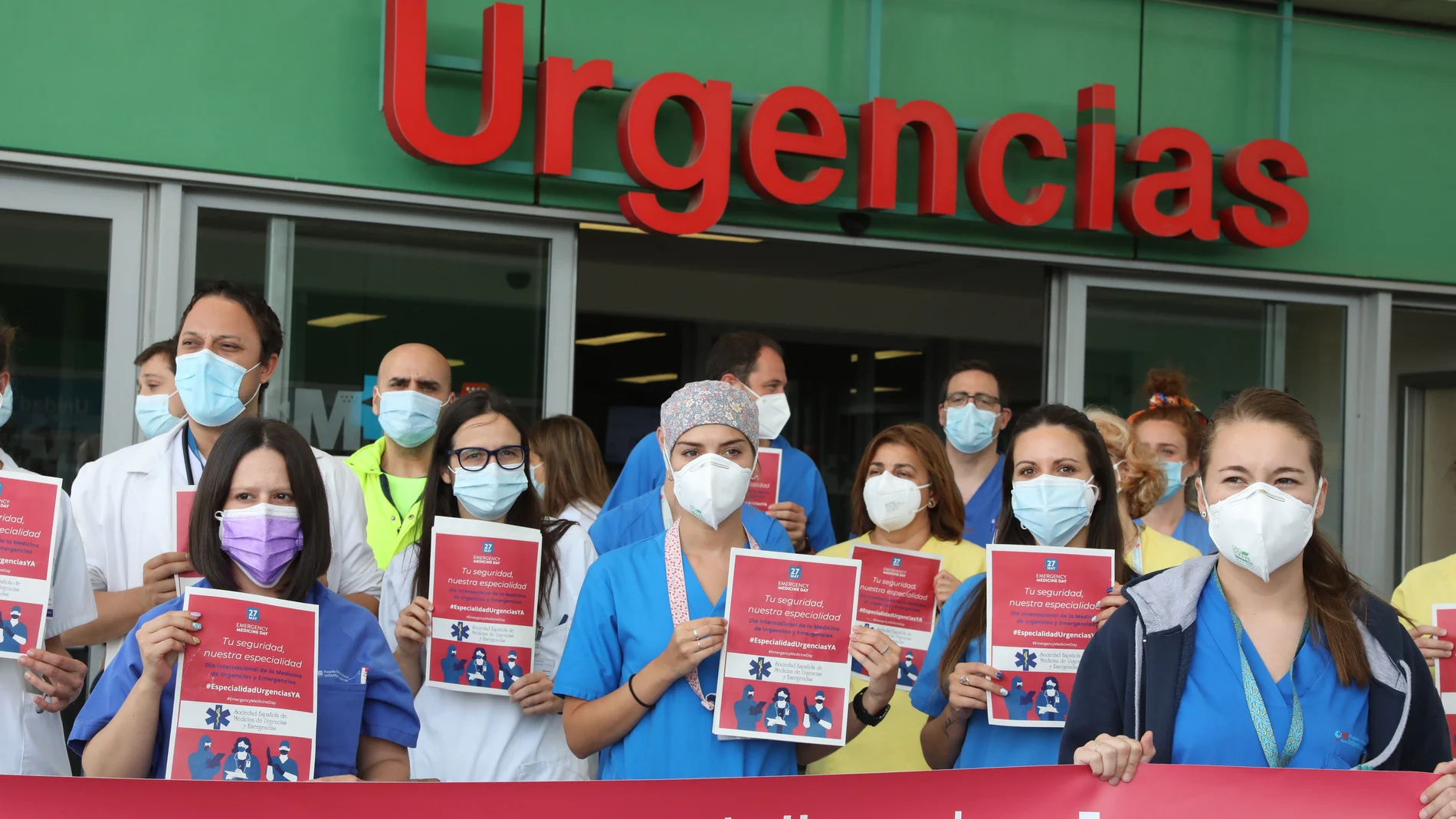 Varios profesionales sanitarios de los servicios de Urgencias y Emergencias con carteles, durante una concentración para pedir la creación de su especialidad, en la entrada del Hospital Infanta Leonor, a 27 de mayo de 2021, en Madrid (España).