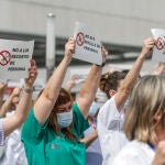 Varias personas de Juntas de Personal de departamentos de Salud con carteles, durante una concentración contra el cese de los contratos refuerzo Covid, en la puerta del Hospital de La Fe, en Valencia