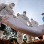 - Voluntarios vestidos con trajes de protección entierran el cuerpo de un fallecido por Covid-19,